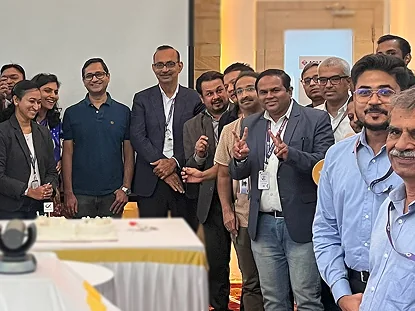 QKTech colleagues gathered around a celebration cake at the Breakfast Club